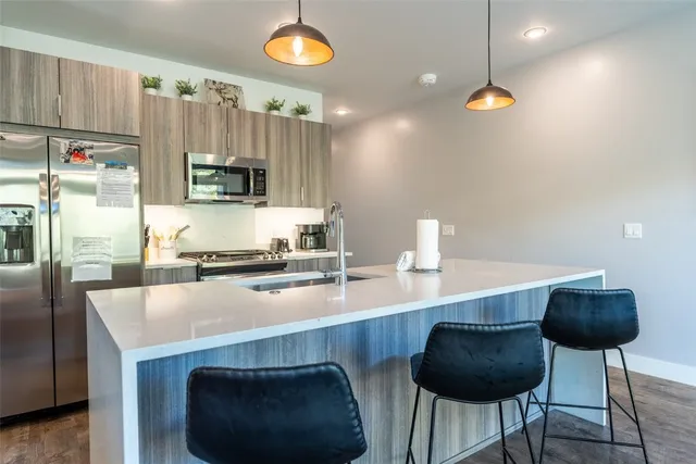 a kitchen with kitchen island a stove a sink a refrigerator and chairs