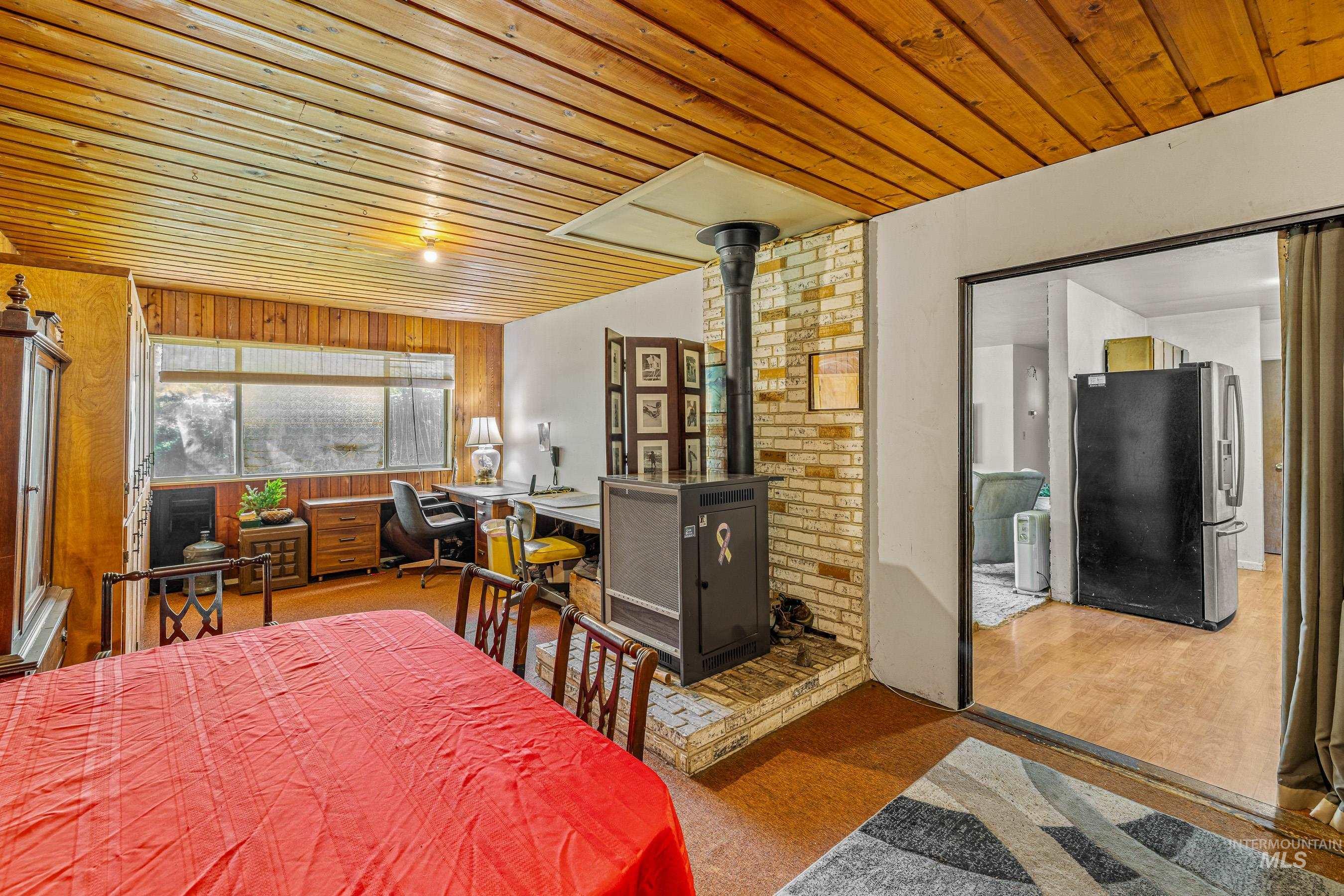 7026 S Highway Riggins, ID 83549 - Photo 21 of 50 Wood-paneled ceilings and walls, brick accent wall, wood-burning stove, and wood-finish flooring