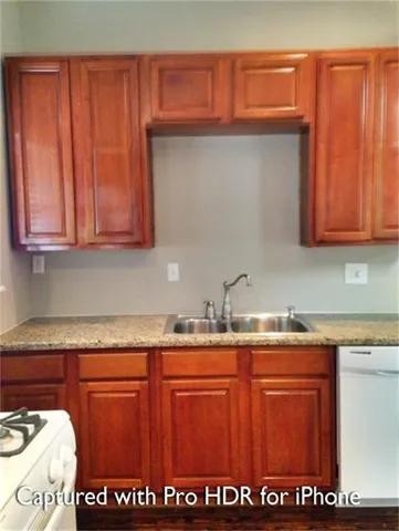 a kitchen with granite countertop a sink window and cabinets