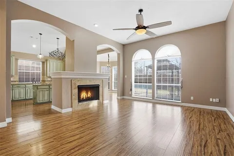 a view of a livingroom with wooden floor a fireplace and windows