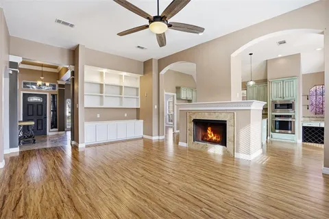 a view of a livingroom with fireplace wooden floor and a ceiling fan