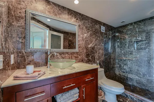 a bathroom with a granite countertop sink a mirror and a shower
