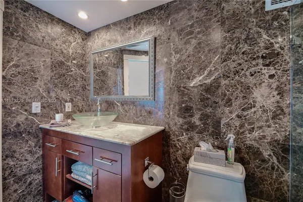 a bathroom with a granite countertop sink a mirror and shower