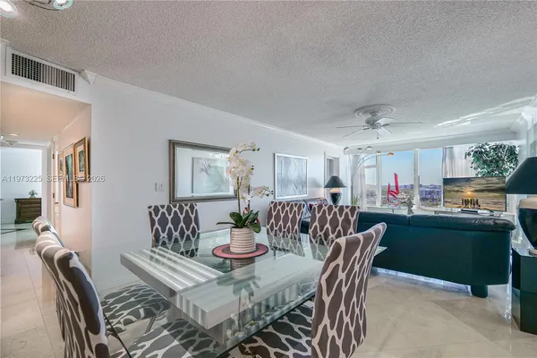 a view of a dining room and livingroom with furniture wooden floor a rug a painting and a chandelier