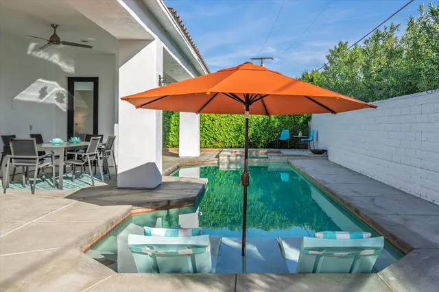 a view of pool with lawn chairs under an umbrella