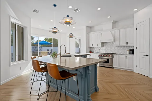 a kitchen with stainless steel appliances granite countertop a sink a stove a refrigerator and island with wooden floor