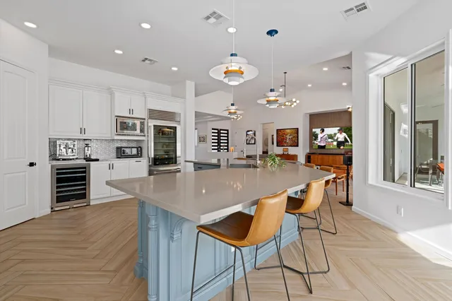 a large kitchen with stainless steel appliances kitchen island granite countertop a large kitchen island a stove a refrigerator a oven a dining table and chairs with wooden floor