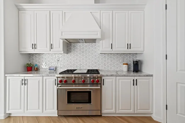 a kitchen with granite countertop white cabinets and stainless steel appliances