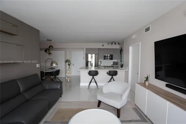 a living room with furniture a flat screen tv and kitchen view