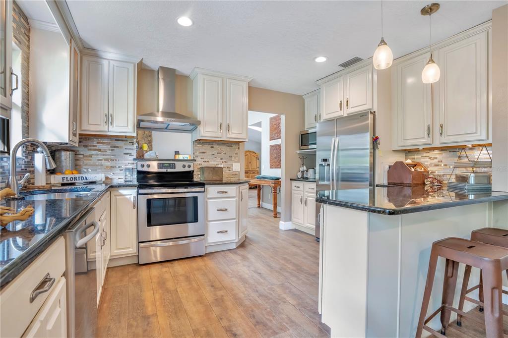 9488 Shortleaf Court Apopka, FL 32703 - Photo 26 of 60 a kitchen with stainless steel appliances white cabinets a sink a stove a refrigerator and island