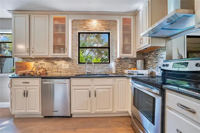 a kitchen with stainless steel appliances granite countertop white cabinets and a window