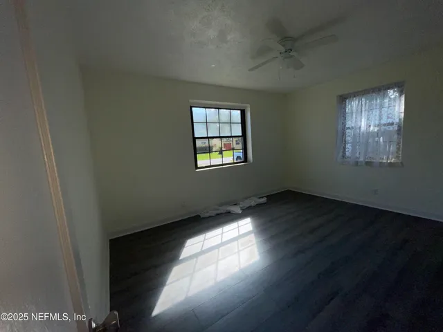 an empty room with wooden floor and windows