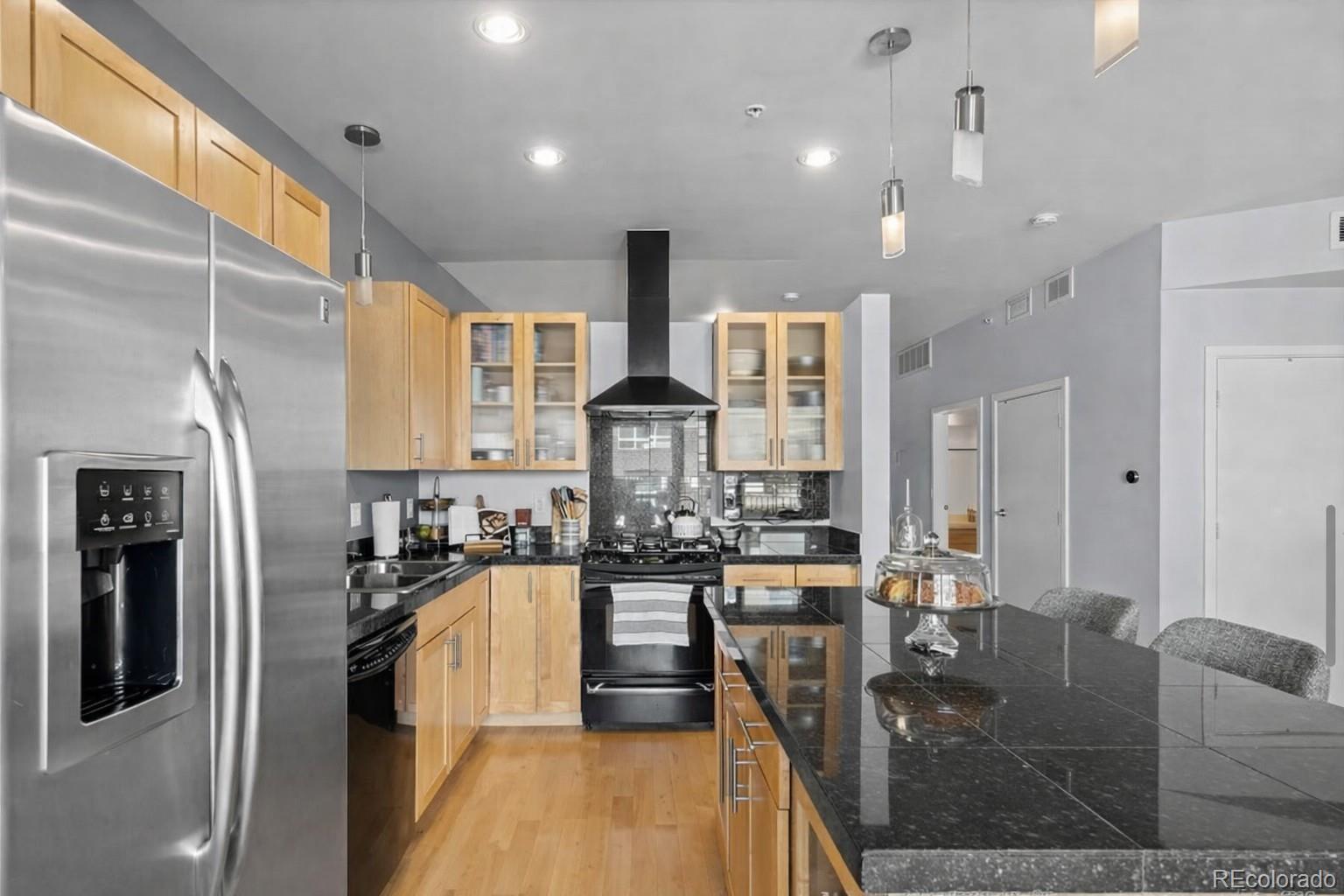 1438 Little Raven Street, Unit 310 Denver, CO 80202 - Photo 11 of 24 a kitchen with stainless steel appliances kitchen island granite countertop a refrigerator a oven a sink dishwasher and couches with wooden floor