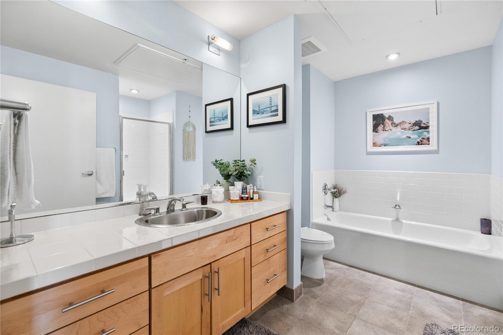 1438 Little Raven Street, Unit 310 Denver, CO 80202 - Photo 16 of 24 a bathroom with double vanity sinks a large mirror a bathtub and a toilet