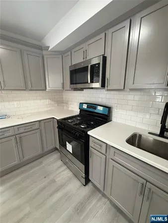 a kitchen with granite countertop a sink stainless steel appliances and cabinets