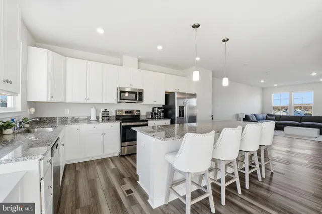 a kitchen with stainless steel appliances kitchen island granite countertop a dining table chairs and sink