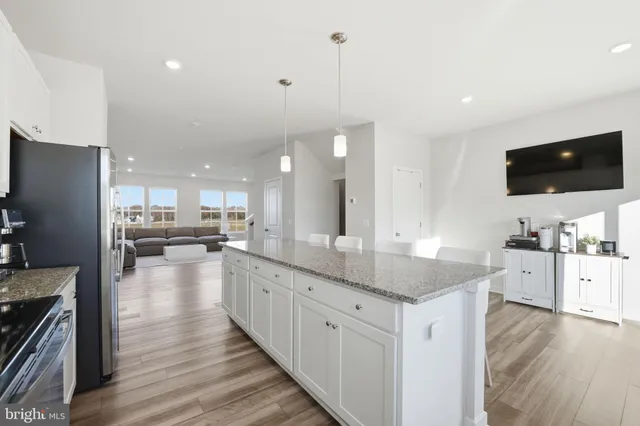 a large kitchen with kitchen island a sink dishwasher stove and white cabinets with wooden floor
