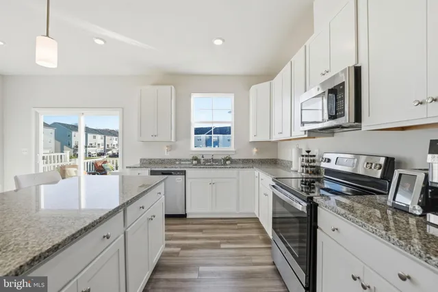 a kitchen with granite countertop stainless steel appliances sink stove and cabinets