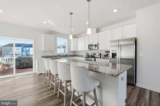 a kitchen with stainless steel appliances granite countertop a table chairs refrigerator and wooden floor