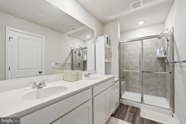 a bathroom with a double vanity sink mirror and shower