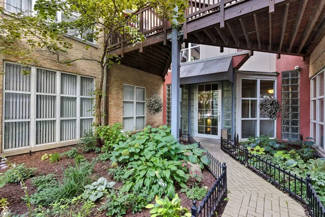 a view of a house with potted plants and a large tree
