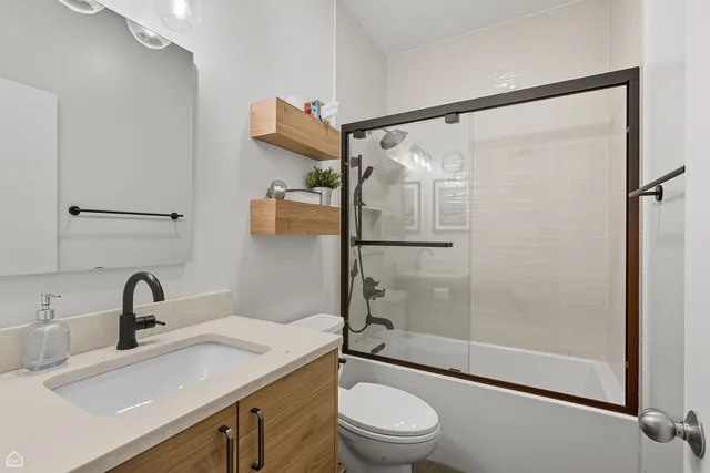 a bathroom with a shower sink vanity mirror and toilet