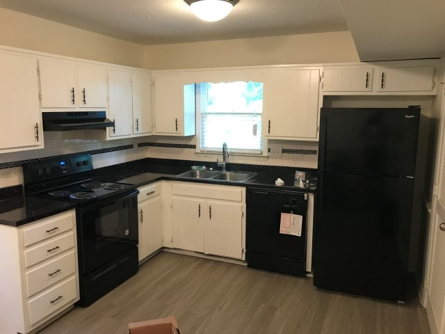 1228 Gorman Street Raleigh, NC 27606 - Photo 7 of 10 a kitchen with granite countertop white cabinets and black appliances