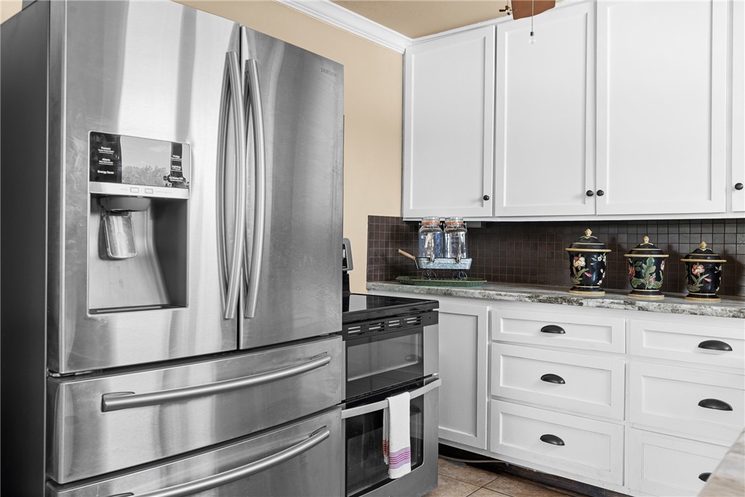10415 McKnight Road Brenham, TX 77833 - Photo 12 of 23 a kitchen with stainless steel appliances white cabinets and a refrigerator