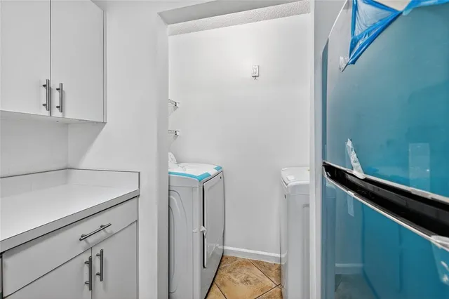 a view of a kitchen with refrigerator and white cabinets