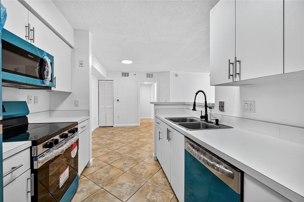 2011 Renaissance Boulevard, Unit 101 Miramar, FL 33025 - Photo 20 of 32 a kitchen with stainless steel appliances a sink a stove and a microwave