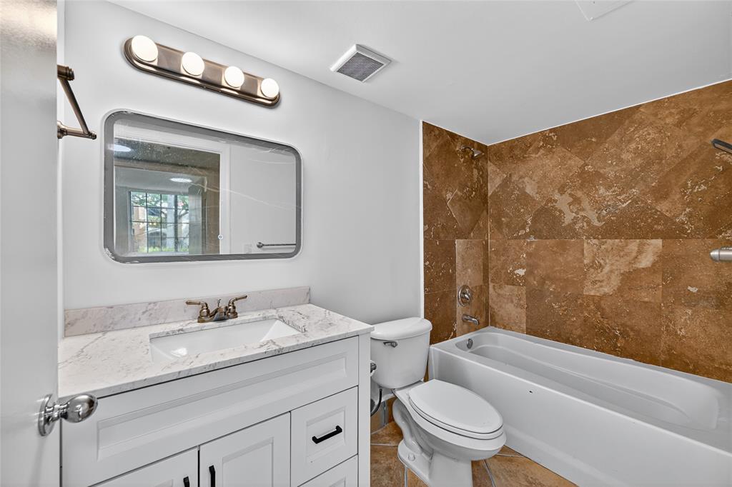 2011 Renaissance Boulevard, Unit 101 Miramar, FL 33025 - Photo 25 of 32 a bathroom with a granite countertop toilet a sink and a mirror