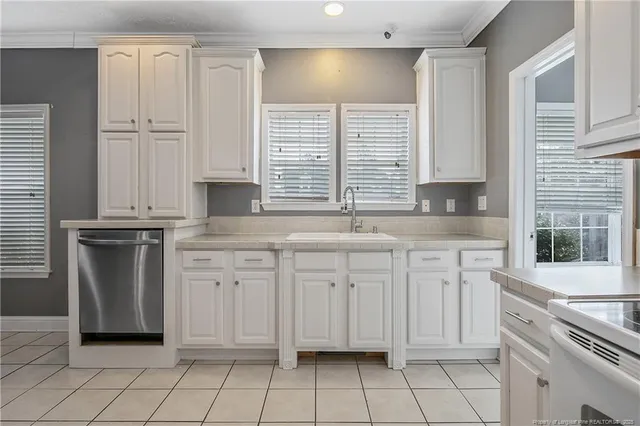 a kitchen with granite countertop white cabinets white appliances a sink and a window