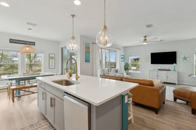 a kitchen that has a sink a counter top space and living room view