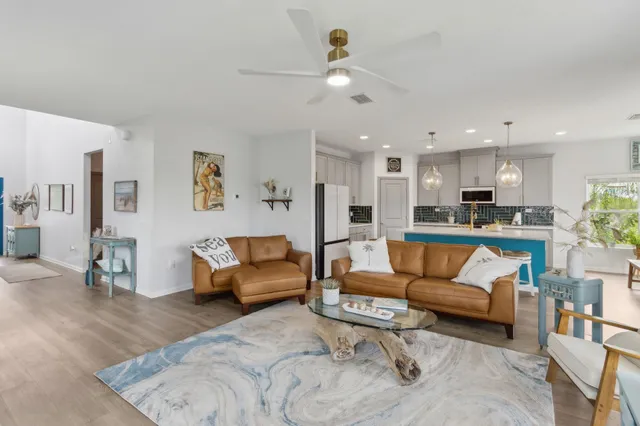 a view of living room kitchen with a couch and a dining table with wooden floor