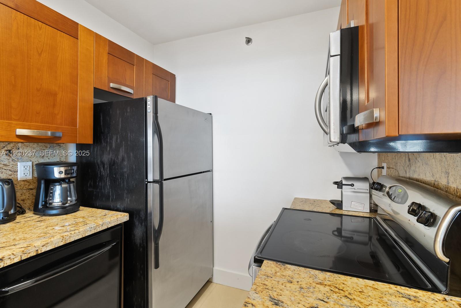 100 Lincoln Road, Unit 543 Miami Beach, FL 33139 - Photo 6 of 17 a kitchen with stainless steel appliances granite countertop a refrigerator a stove and a sink with wooden floor