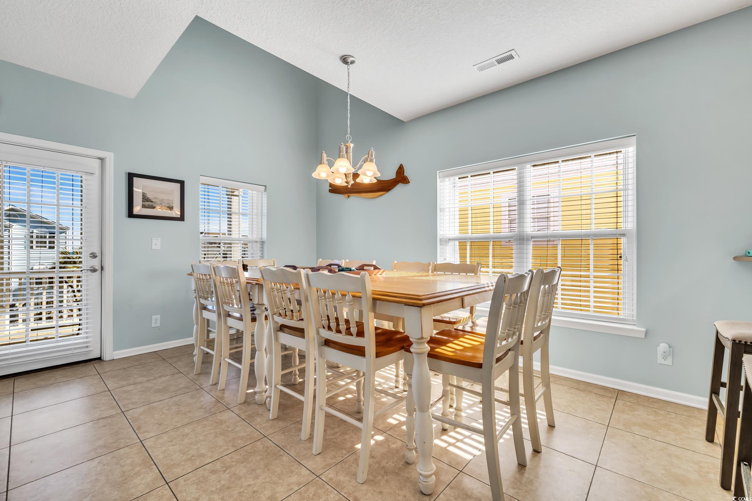 512 North Ocean Boulevard Surfside Beach, SC 29575 - Photo 4 of 39 Dining area with lofted ceiling, a healthy amount of sunlight, visible vents, and an inviting chandelier