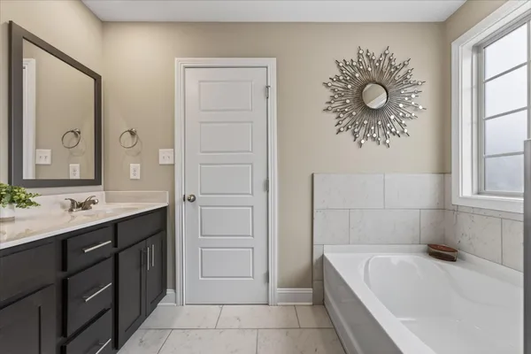 a bathroom with a tub sink and mirror