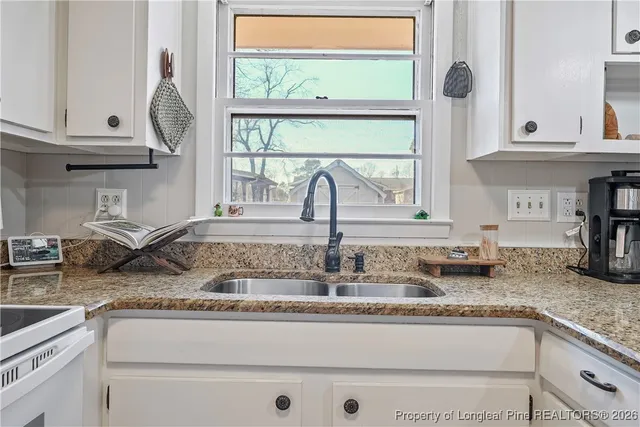 a kitchen with granite countertop a sink a stove and cabinets