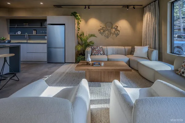 a living room with furniture a refrigerator and kitchen view