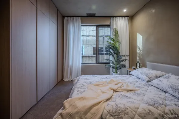 a bedroom with a large bed and windows