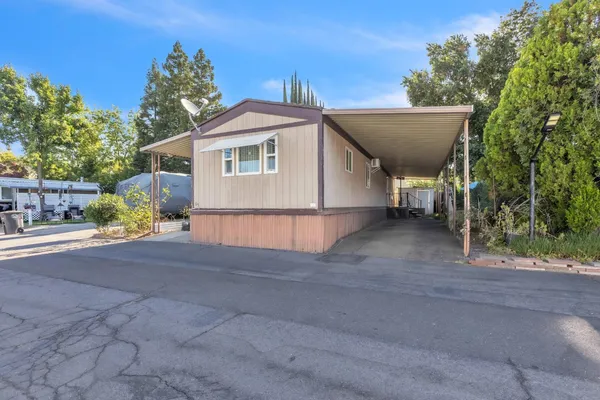 a view of a house with a yard and large tree