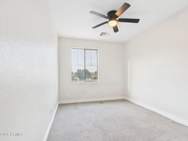 an empty room with a ceiling fan and window