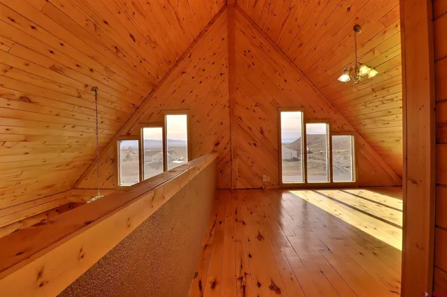 a view of an empty room with wooden floor and windows