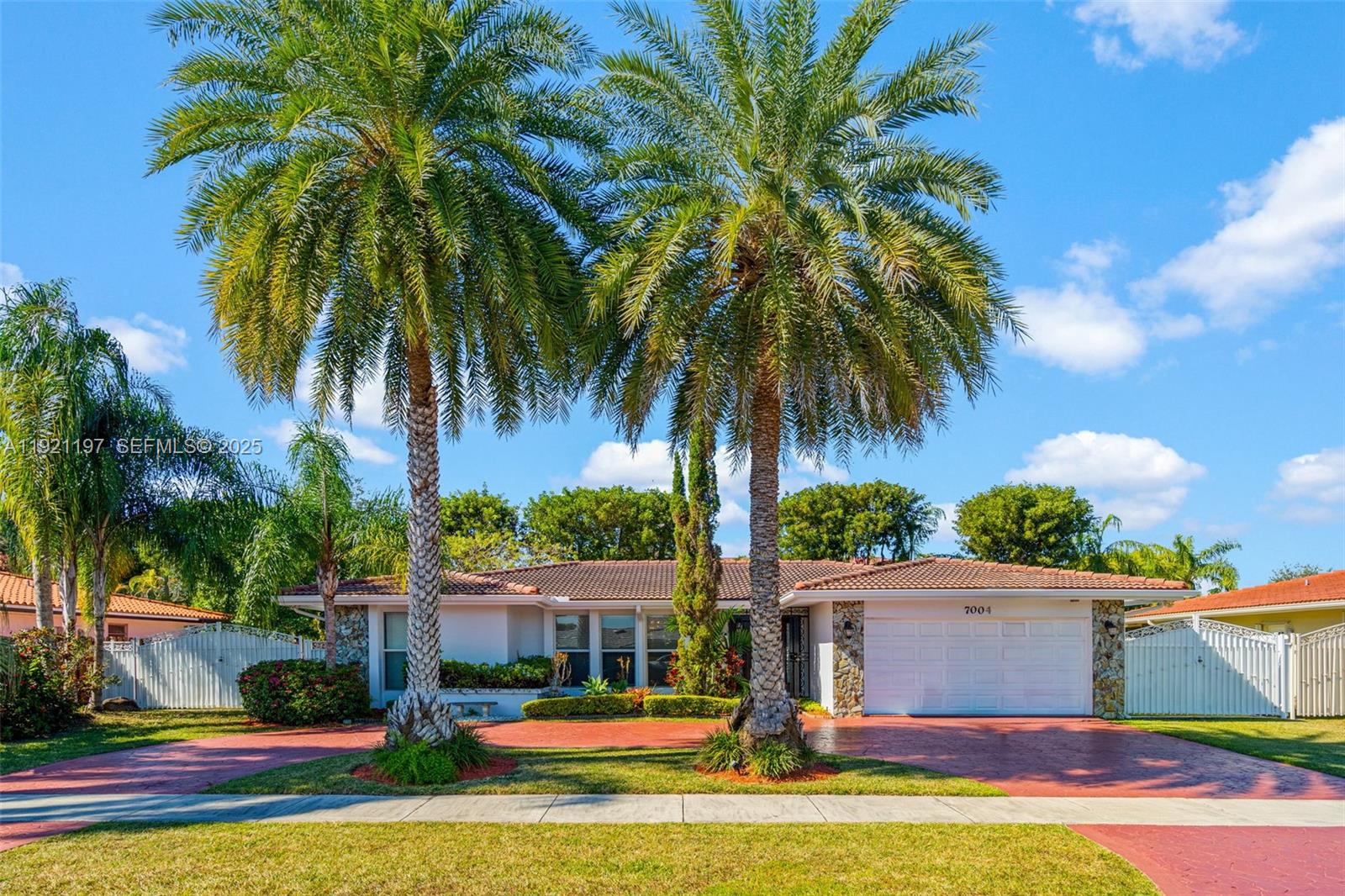 a front view of residential houses with yard and palm tree