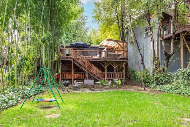 a view of a backyard with a slide trees and wooden fence