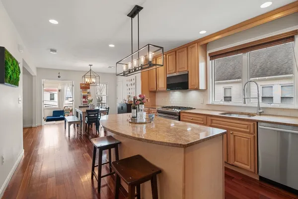 a kitchen with stainless steel appliances granite countertop a stove a sink dishwasher a dining table and chairs with wooden floor