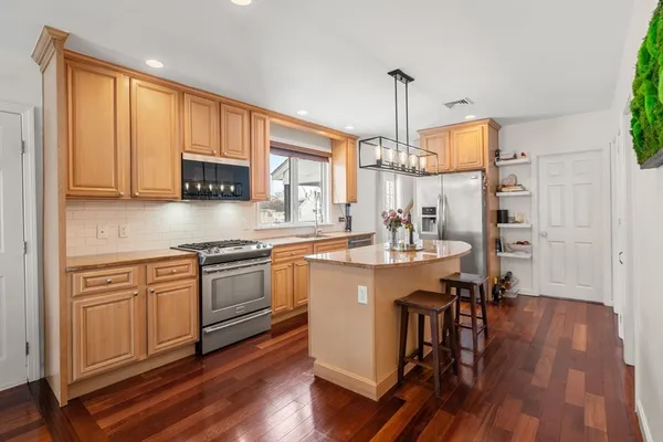 a kitchen with stainless steel appliances granite countertop a sink a stove and a wooden floors