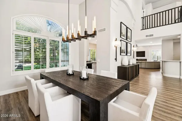 a dining room with wooden floor a chandelier a wooden table and chairs