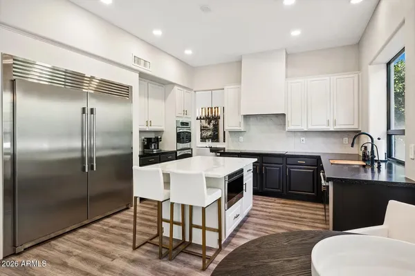 a kitchen with stainless steel appliances granite countertop a refrigerator a sink a stove a dining table and chairs