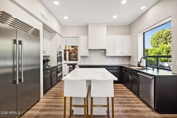 a large kitchen with sink a refrigerator and chairs